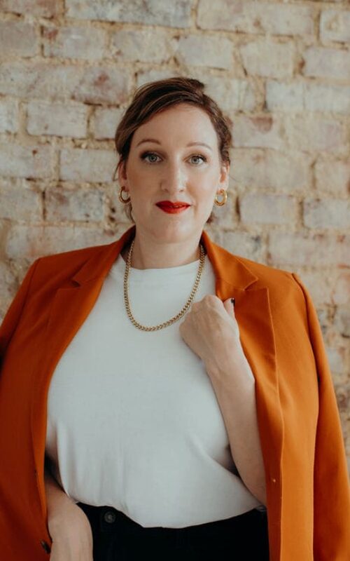 a woman in a white shirt and orange jacket